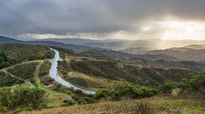 Winding road with storm clouds over the mountains - spring season