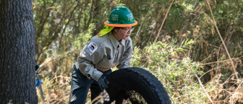 Young woman moving an old tire out of Fisher Creek in Coyote Valley