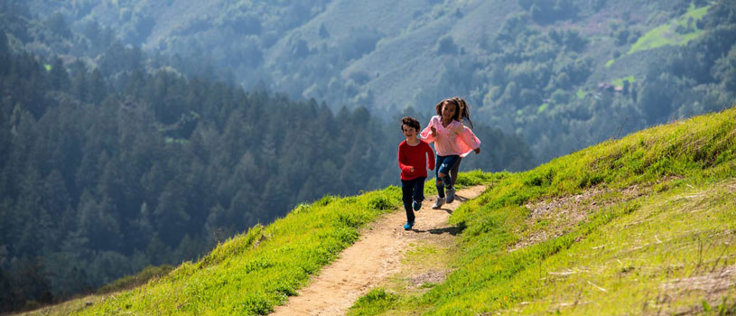 Kids running down trail in green open space